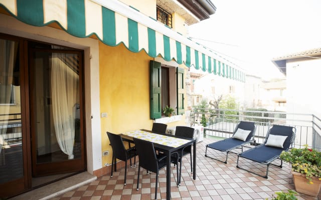 Annonce de FRANCESCA sur misterb&b - Terrazza con tenda elettrica, tavolo con 4 sedie e 2 sdraio dove godere del caldo e sole respirando l'aria fresca del lago di Garda a pochi metri di distranza.
