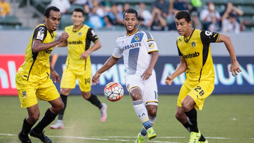 LA Galaxy forward Giovani Dos Santos passes it through some Comunicaciones players