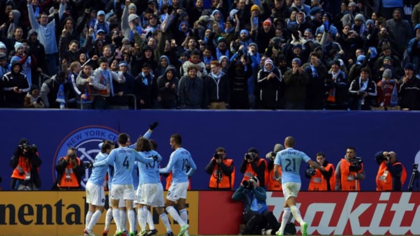 New York City FC celebrate a goal in their first home game with fans cheering in the background