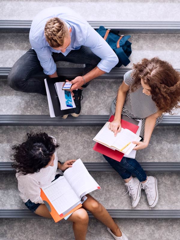 Group of VCE students, sharing notes and discussing as they sit on steps