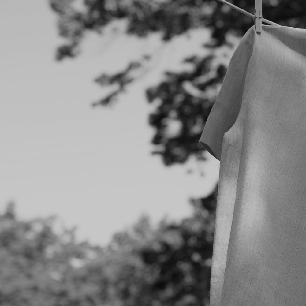 black and white image of a shirt and shorts hanging on a clothesline outside