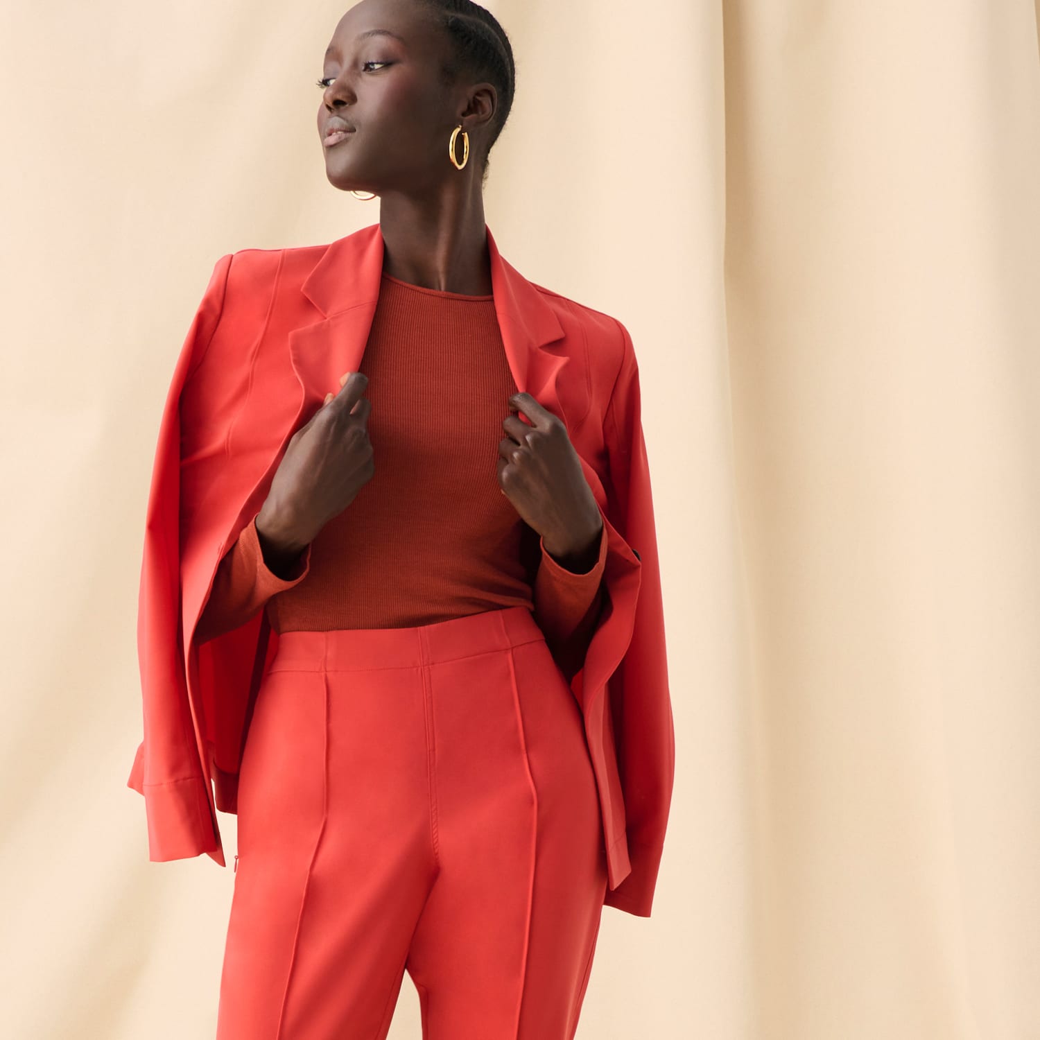 image of a woman standing wearing the moreland and colby in blood orange with the malley top in mars