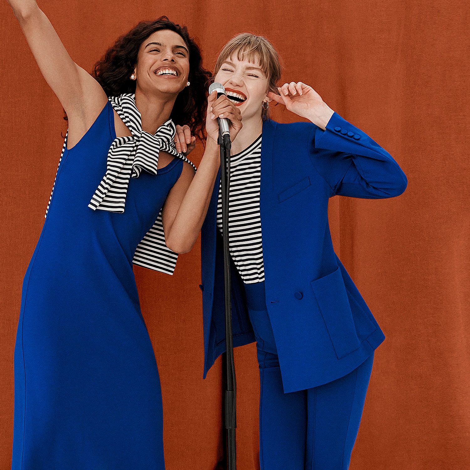 image of 2 women wearing electric blue outfits singing into a microphone