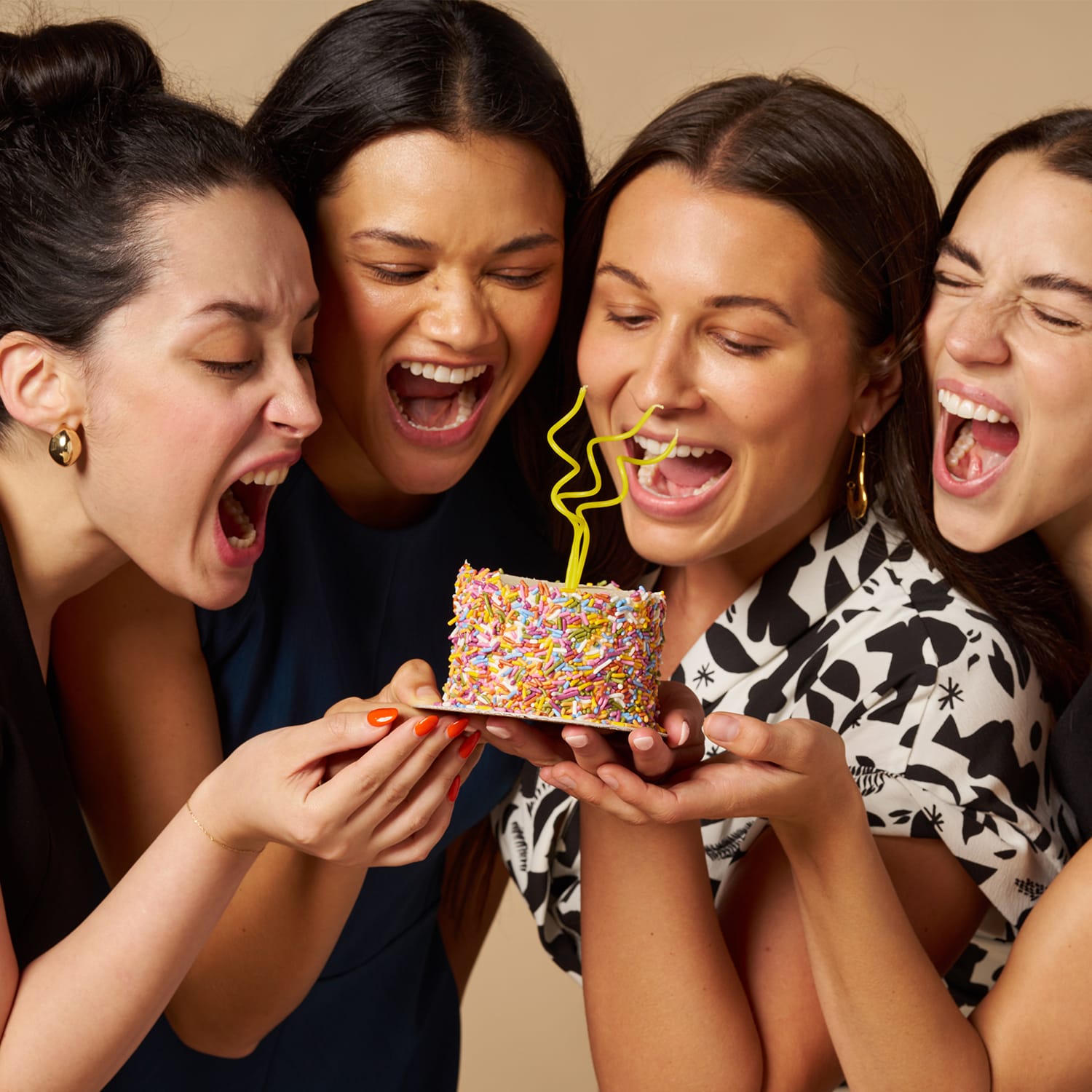 image of four women taking a bit into a cake while wearing the M.M. LaFleur Heritage Dresses