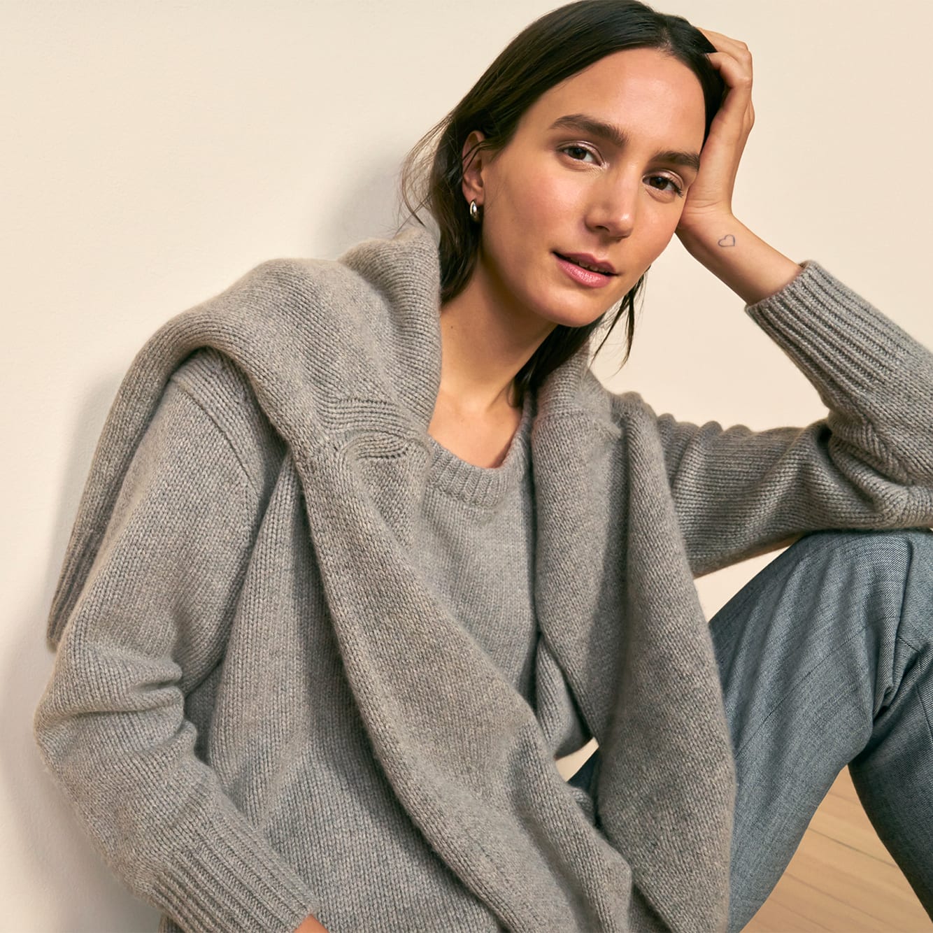 image of a woman sitting wearing the theo sweater in stormcloud with the lea sweater in stormcloud