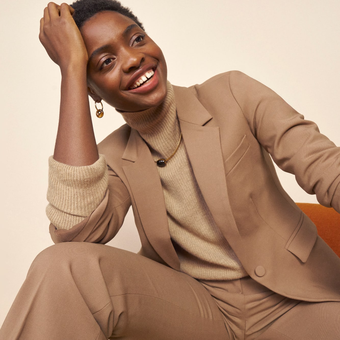 image of a woman wearing the yiyan jacket in camel and the horton pants in camel with the mckenzie sweater in flax