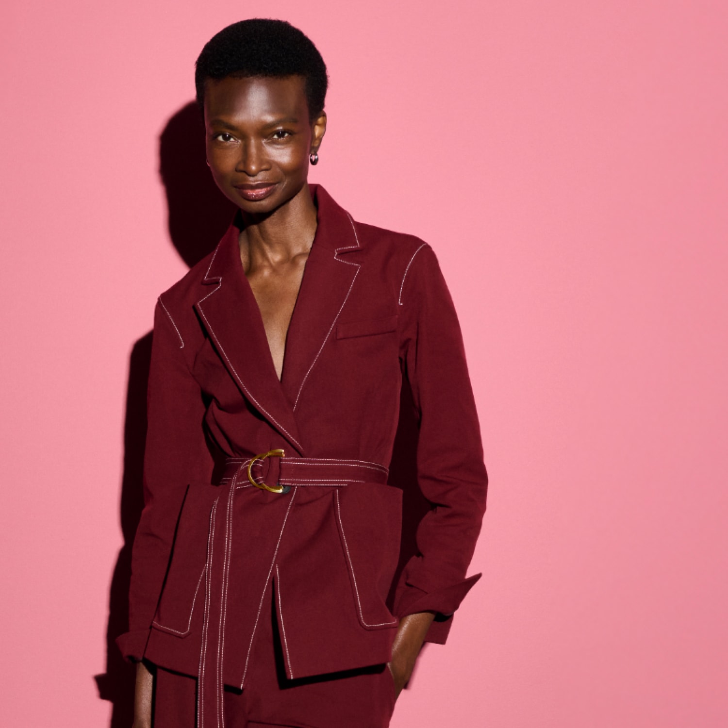 Image of a woman wearing the Grenville jacket in berry jam against a pink background