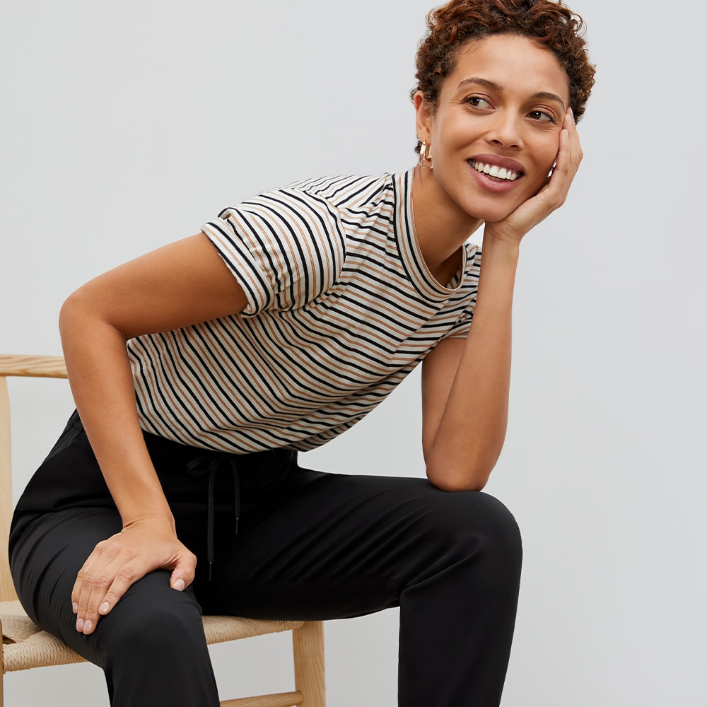 woman sitting in a chair wearing a striped t shirt and looking toward the side