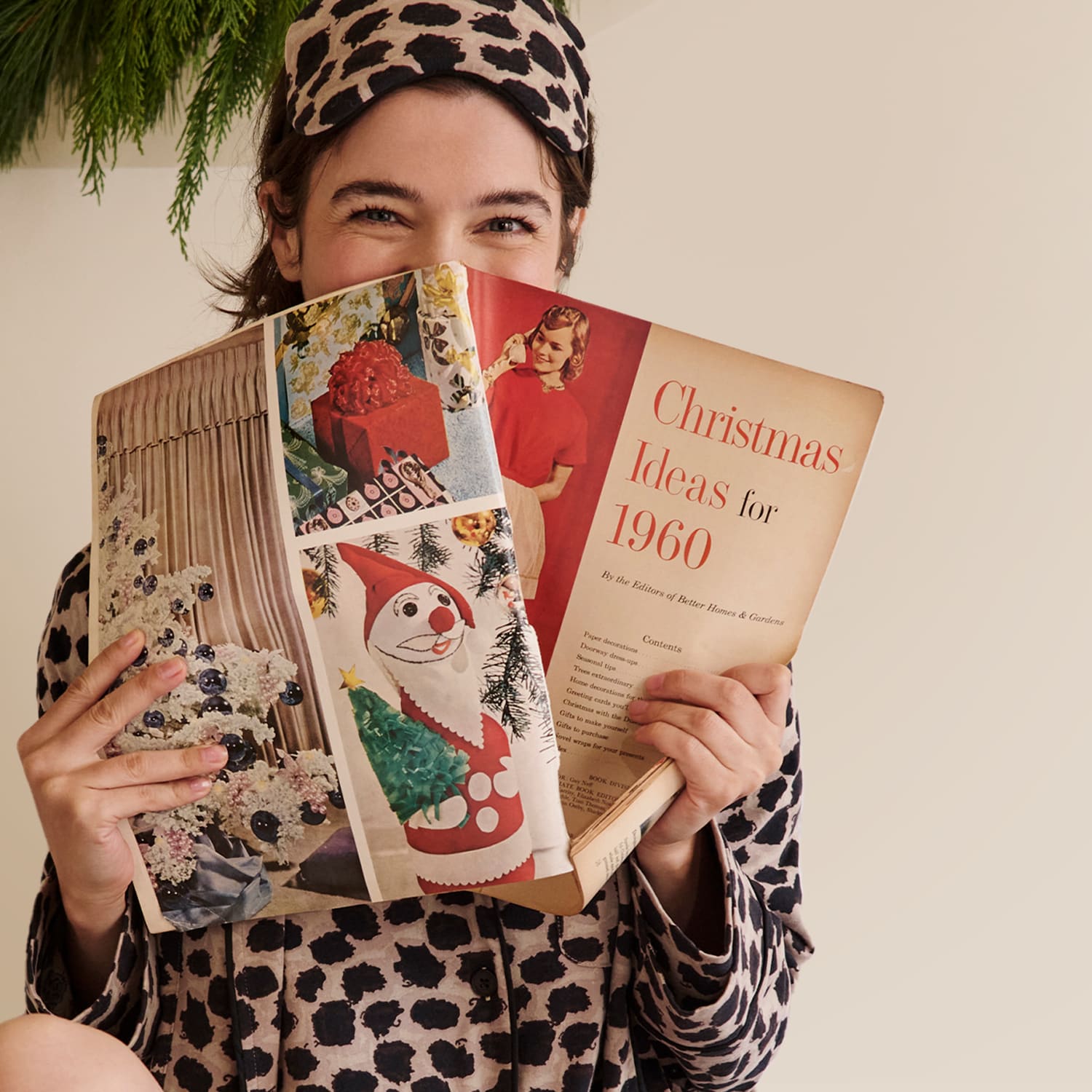 woman sitting in bed wearing sahara print pajamas reading a christmas catalog