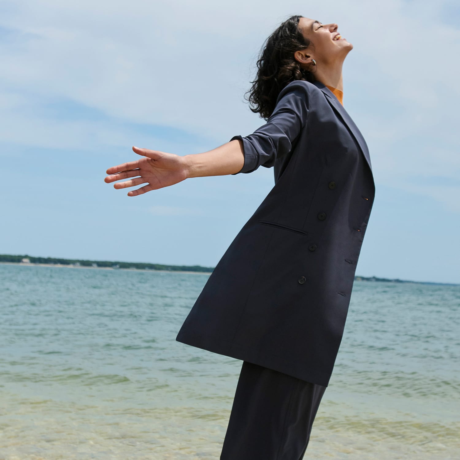 image of a woman standing on a beach wearing the gwynne dress in cool charcoal