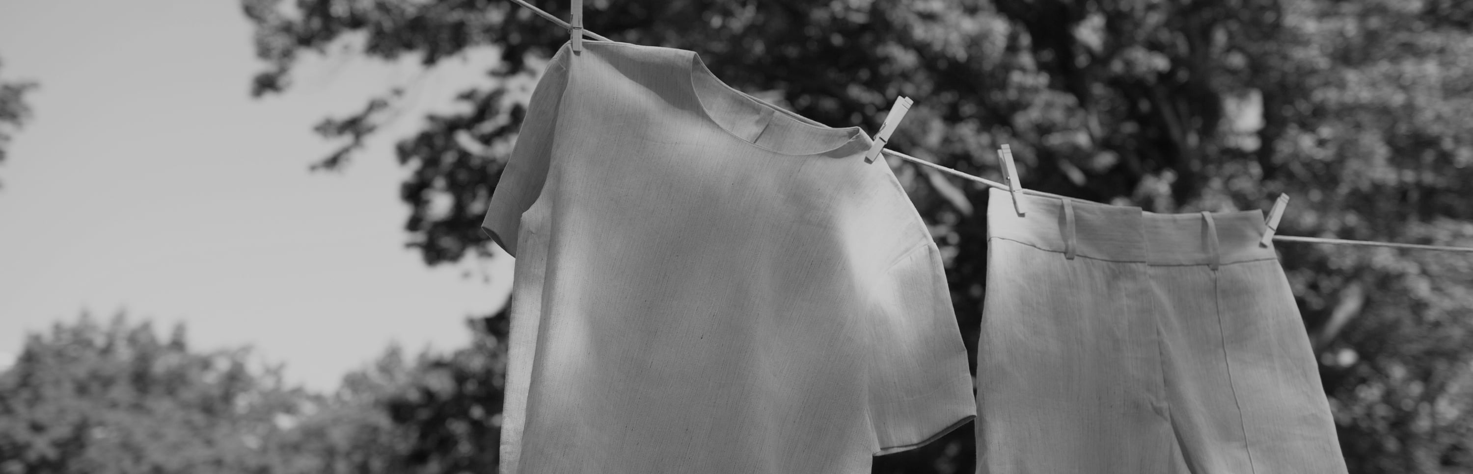 black and white image of a shirt and shorts hanging on a clothesline outside