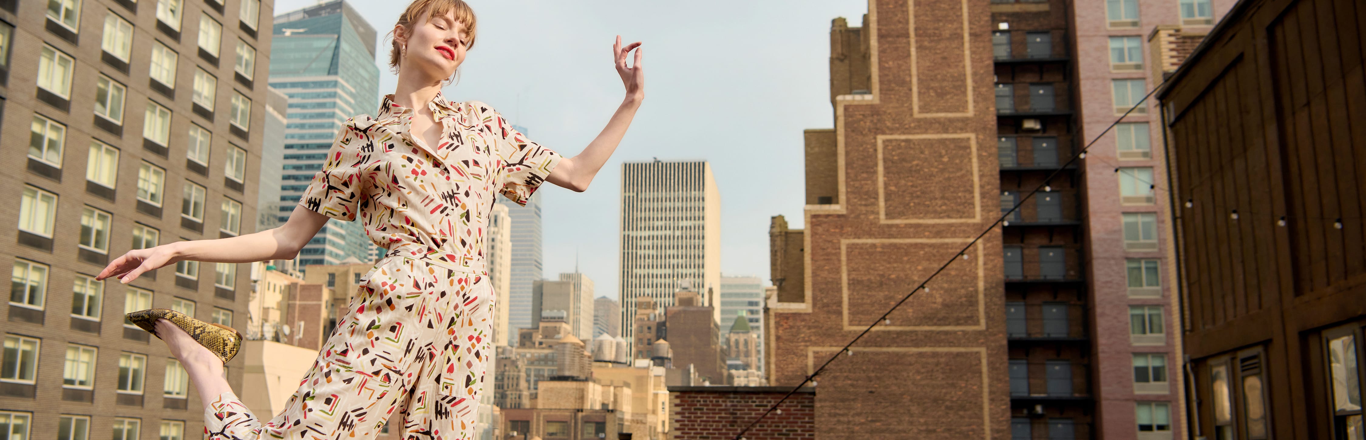 image of a woman dancing on a rooftop wearing the livingston shirt and madelyn pant in rhythm print