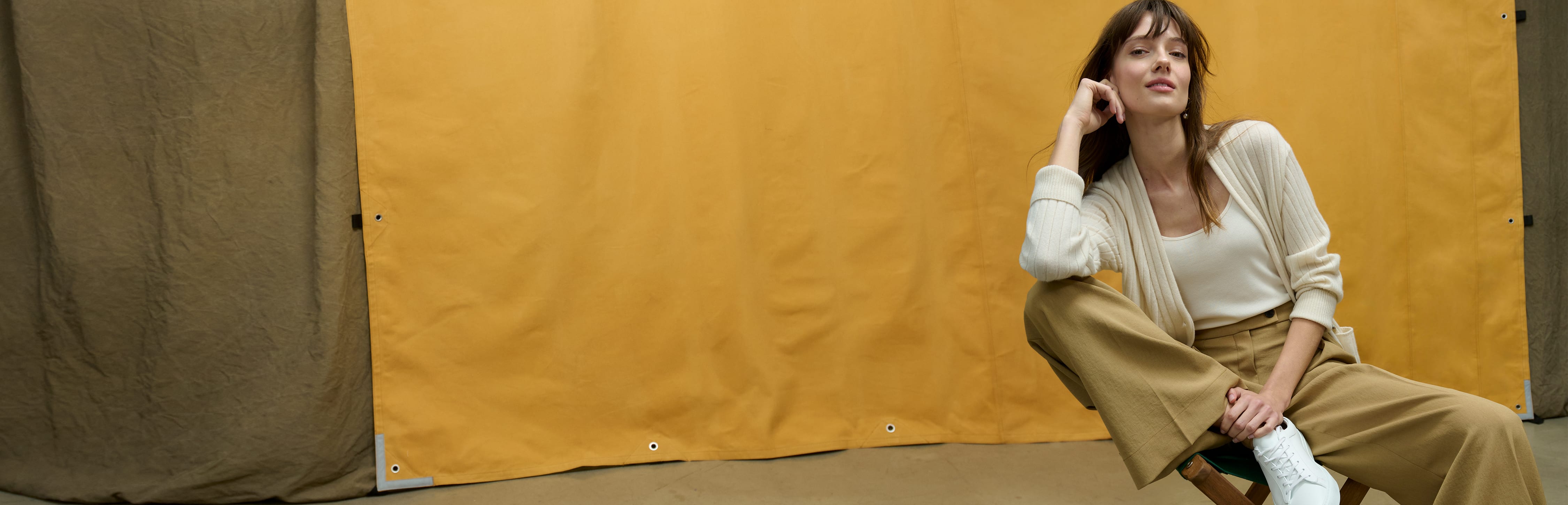 image of a woman sitting on a chair wearing a cream cardigan with tan trousers