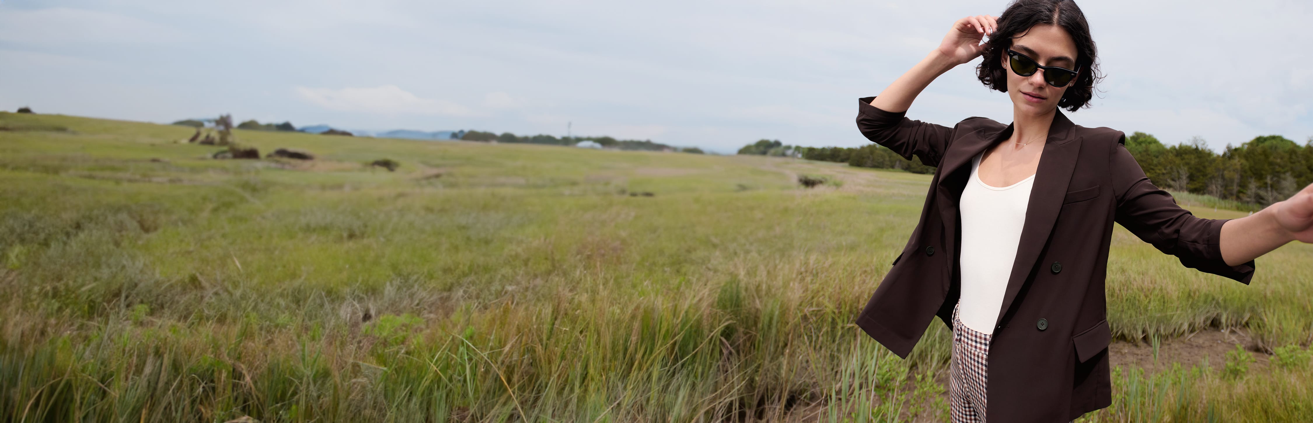 Woman standing in a grassy field, wearing the wine-colored O'Hara blazer in OrigamiTech