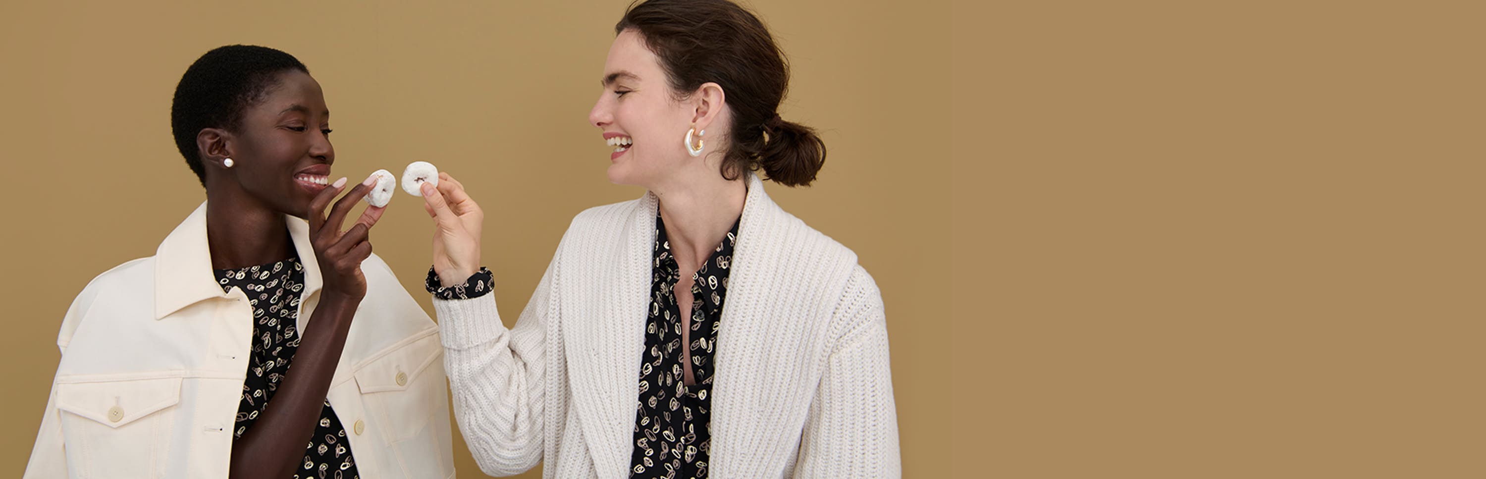 two women cheers-ing with powdered donuts