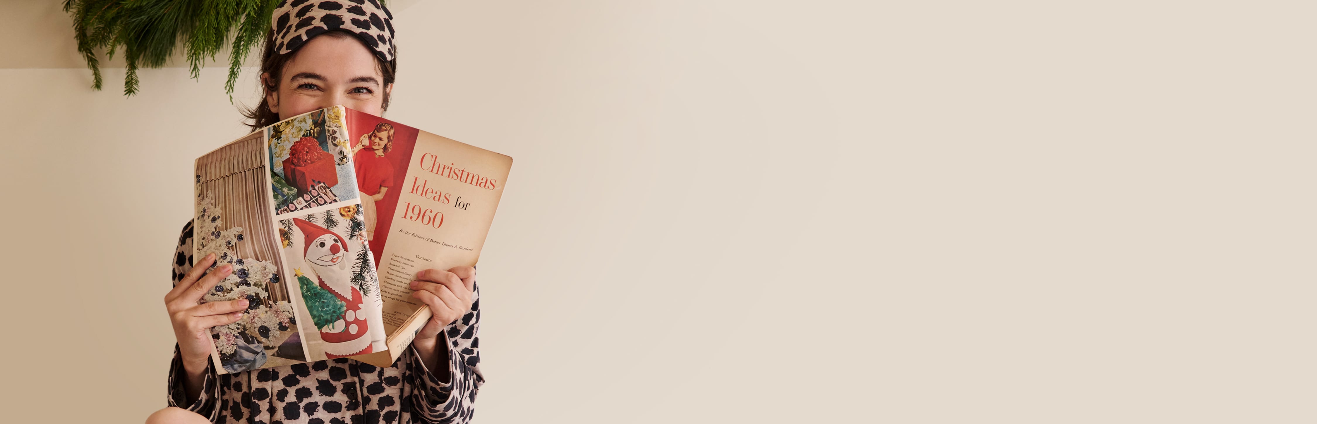 woman sitting in bed wearing sahara print pajamas reading a christmas catalog