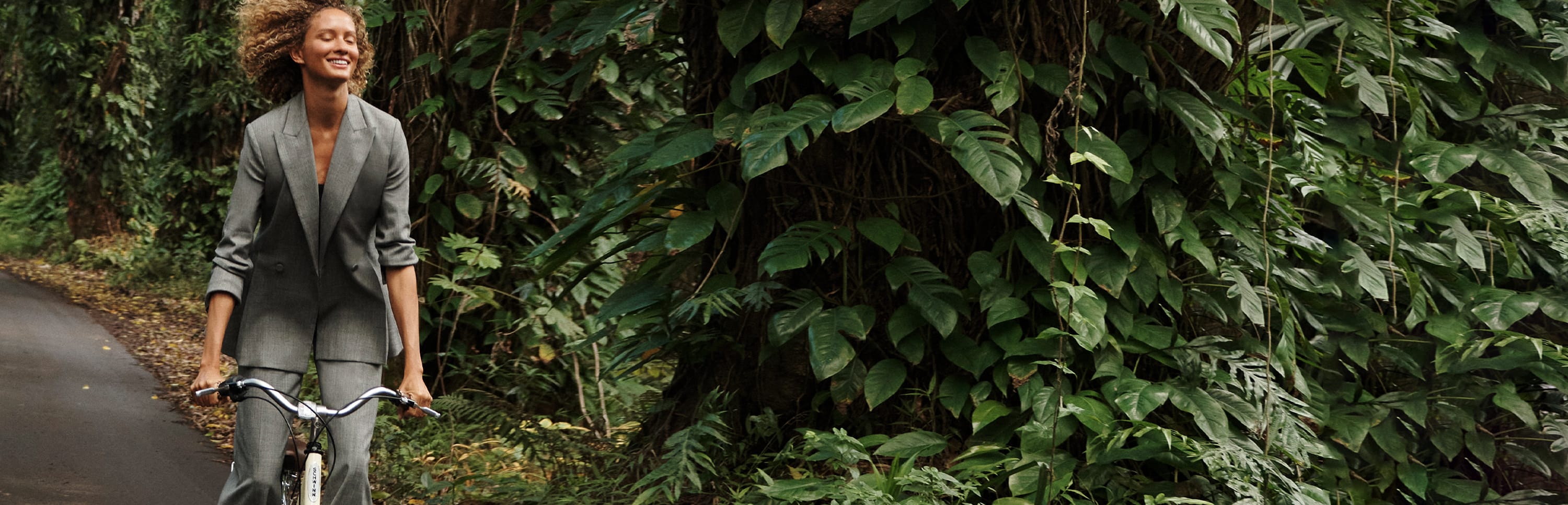 woman riding a bike through a rainforest