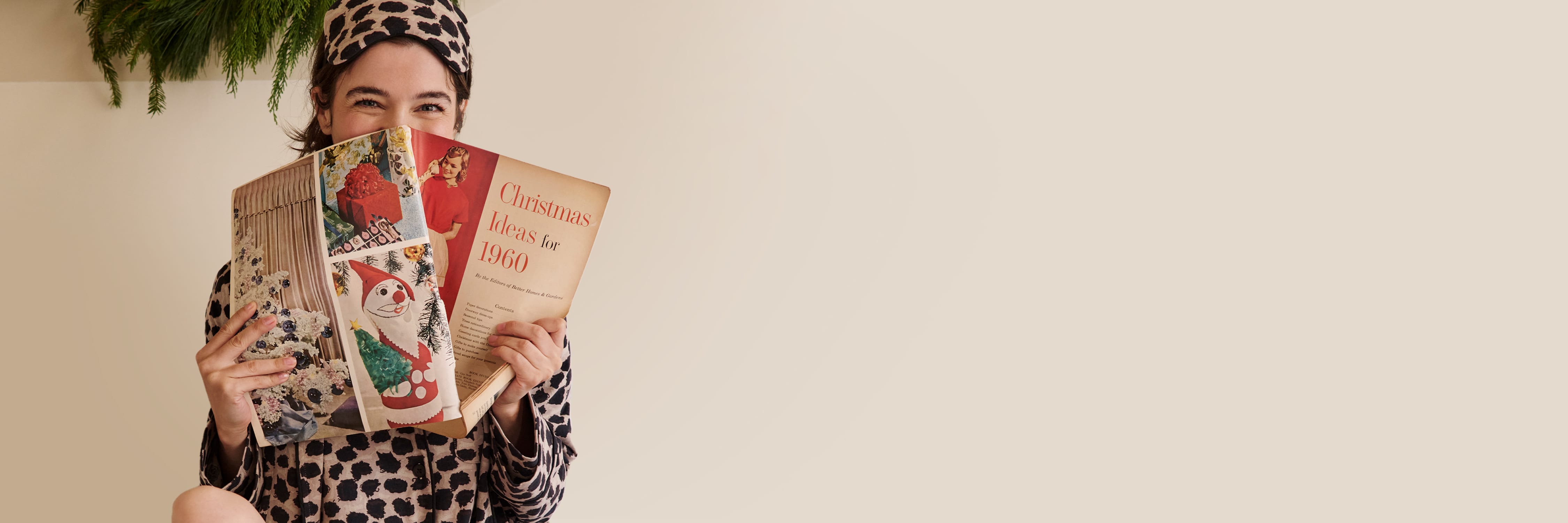 woman sitting in bed wearing sahara print pajamas reading a christmas catalog