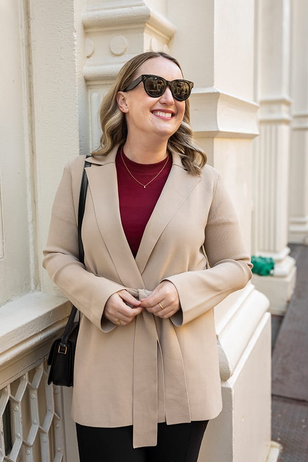 woman wearing a beige jacket over a maroon shirt