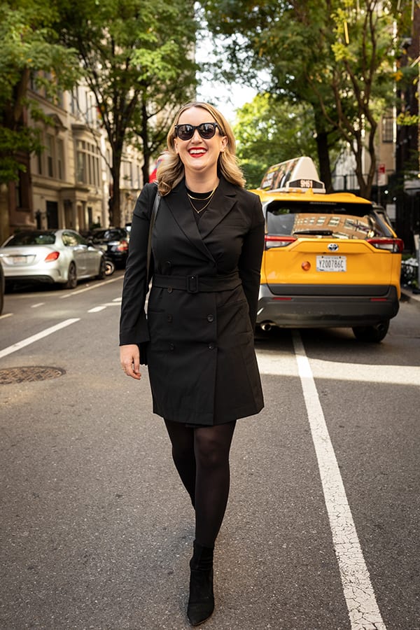 image of a woman walking down the street wearing a black jacket dress