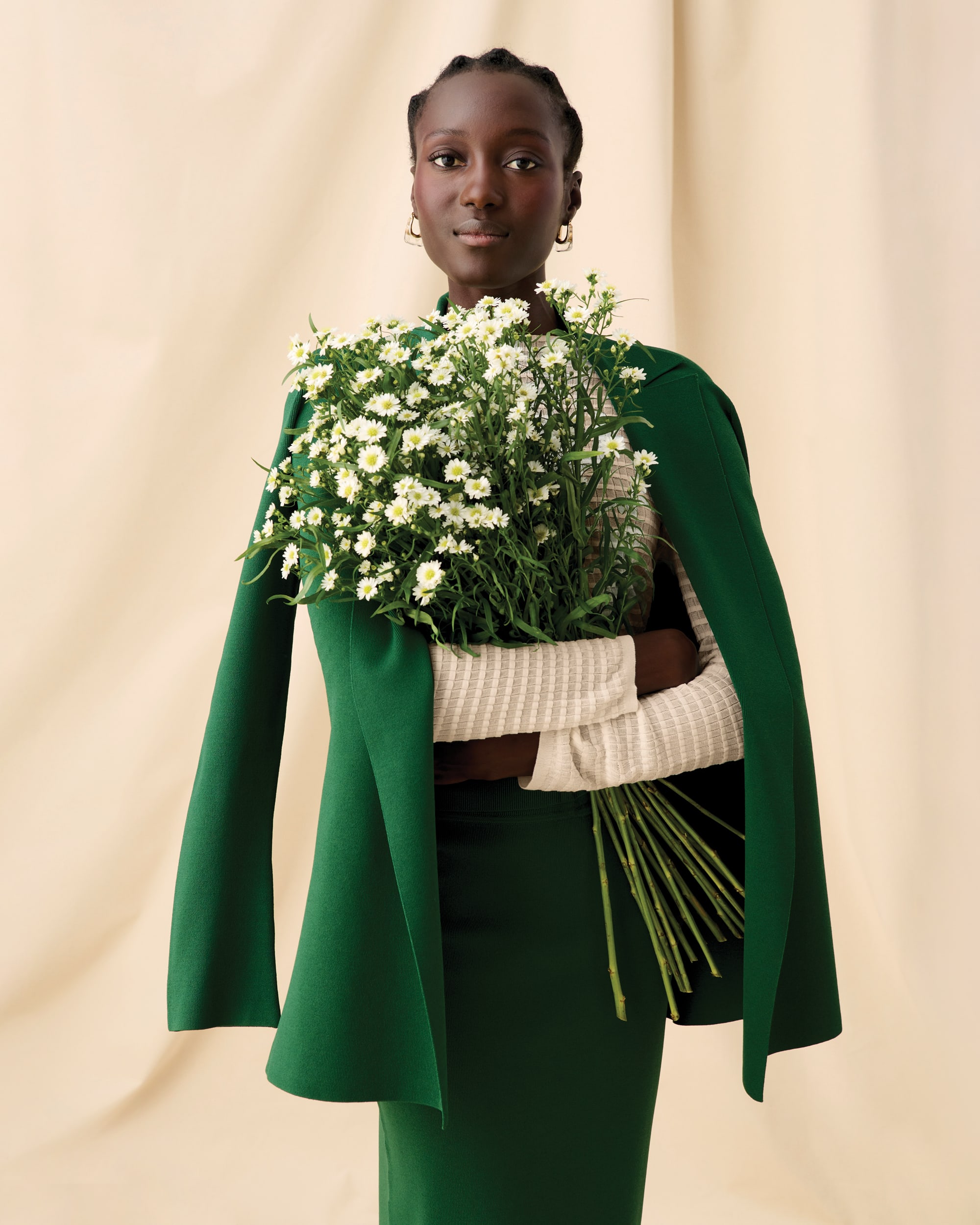 Image of a woman holding flowers wearing the Merritt Jardigan in Vine, Brodie top in meringue, and Harlem skirt in Vine 