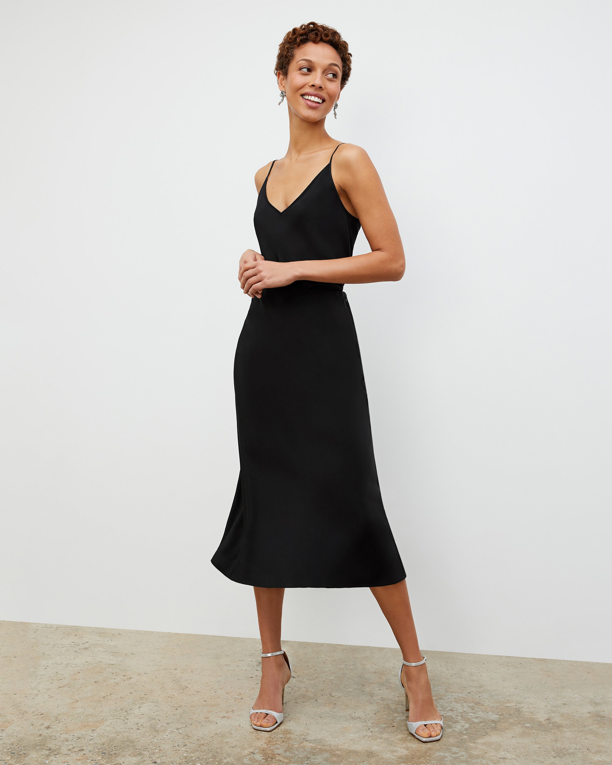 Image of a woman standing wearing the Lisey cami in black and the orchard skirt in black