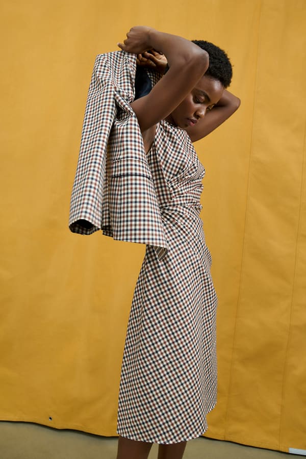 image of a woman wearing the jeannine dress in windowpane putting on the ohara jacket in windowpane