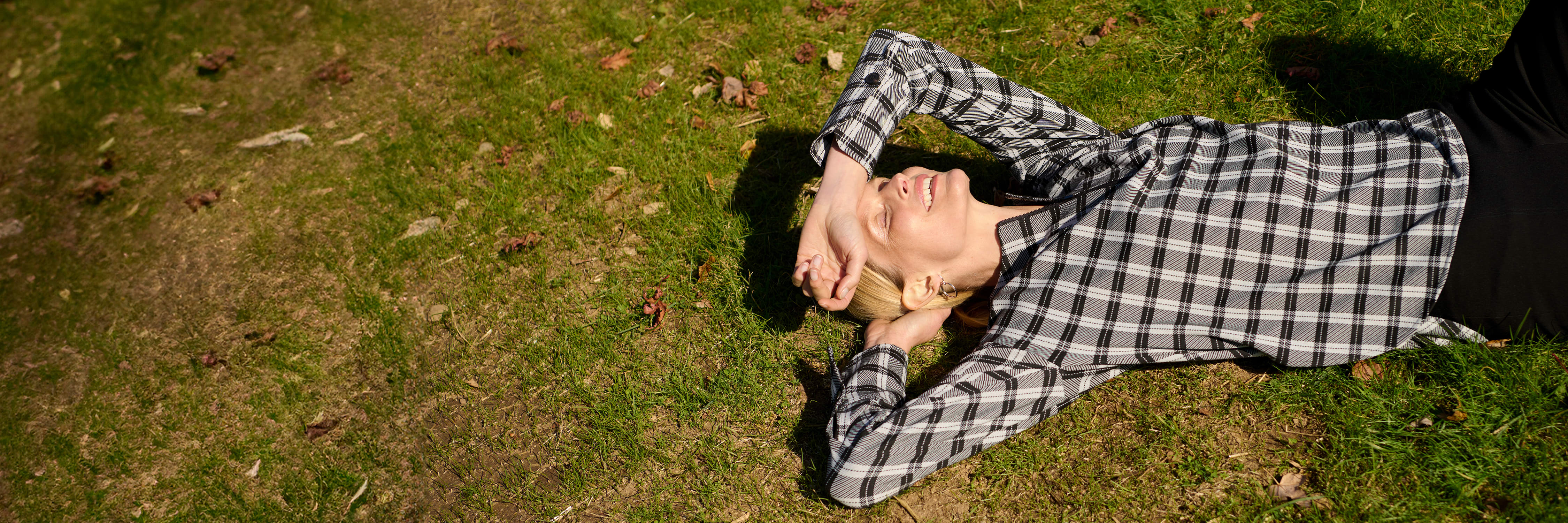 image of a woman wearing a plaid top lying in a yard