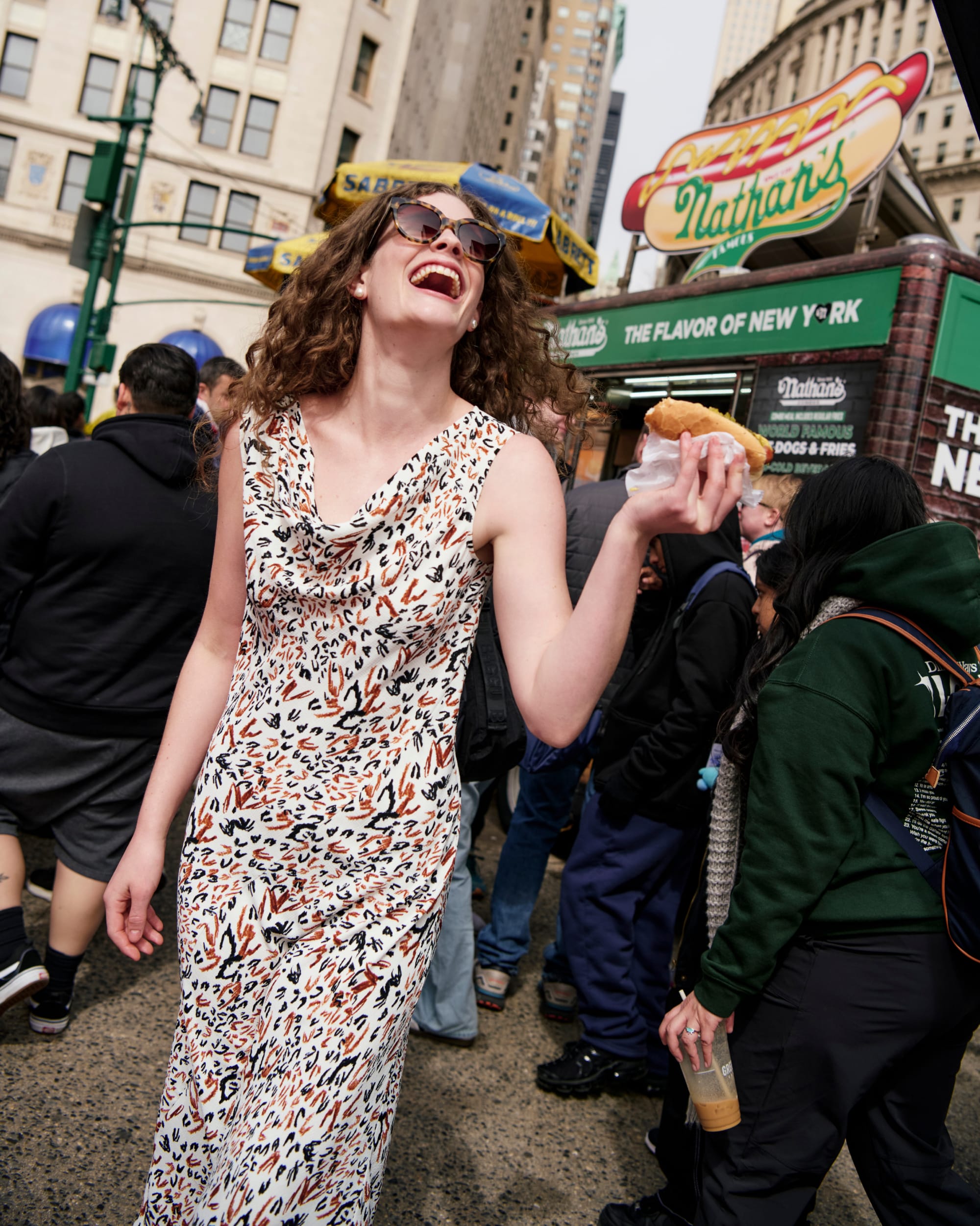 image of a woman wearing the priya dress in leopard sketch holding a hot dog