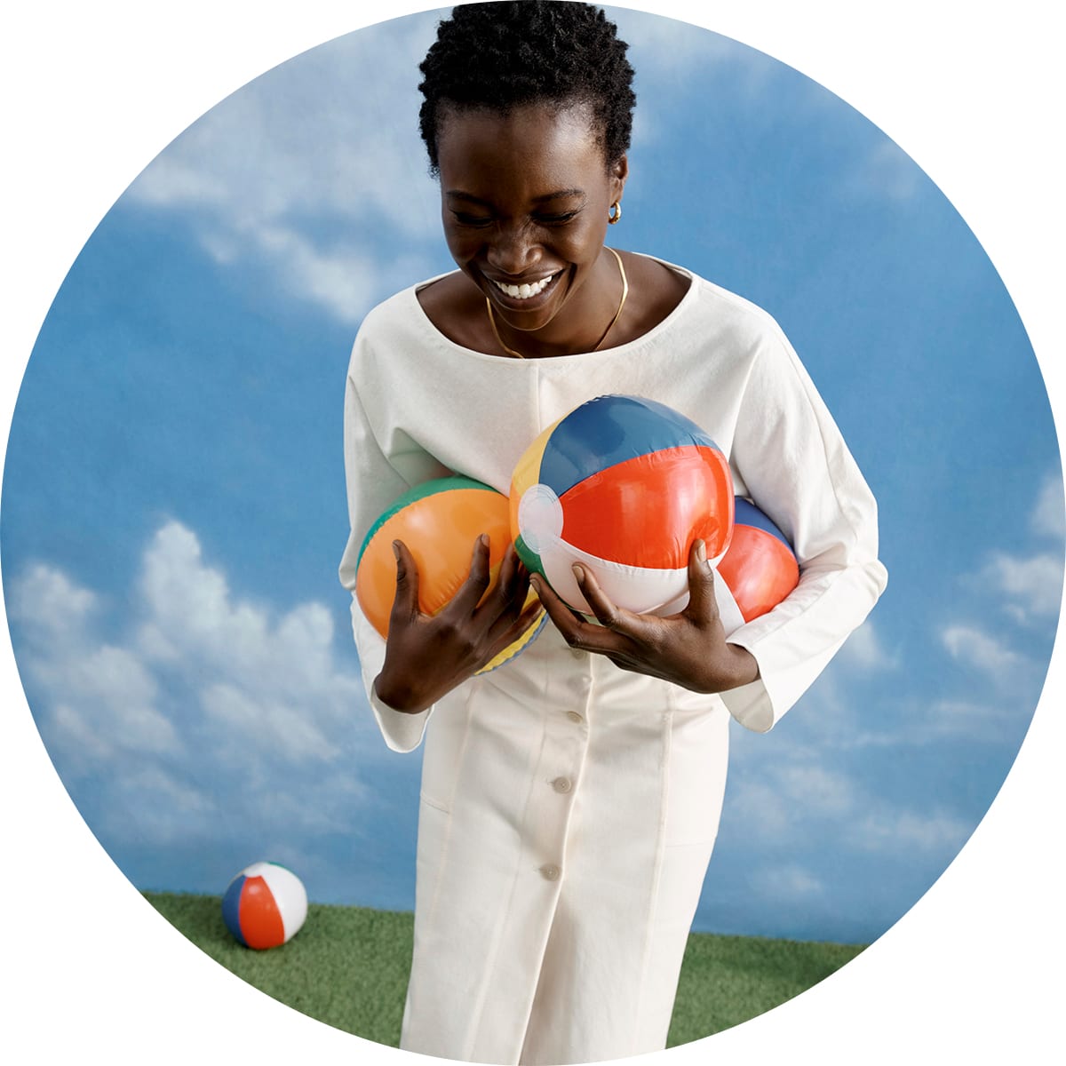 woman wearing M.M.LaFleur's Wren Top and Lane Skirt, holding beach balls 