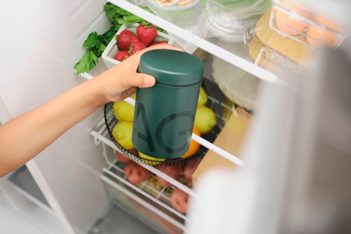 someone taking a green container that says AG on it from the fridge