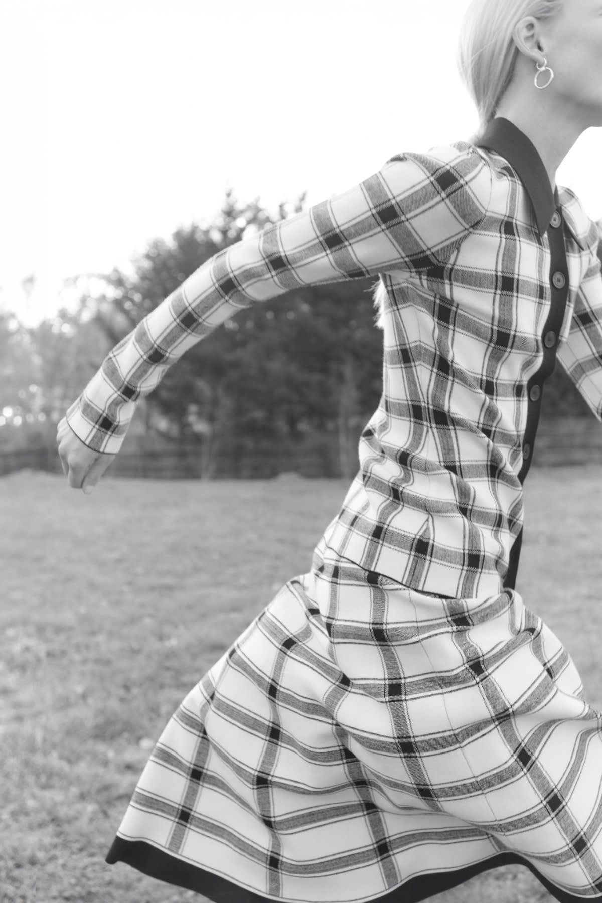 black and white image of woman running and wearing knit plaid top and skirt set