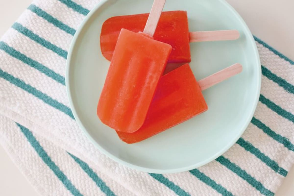 red popsicles on a plate on a blue/white striped towel
