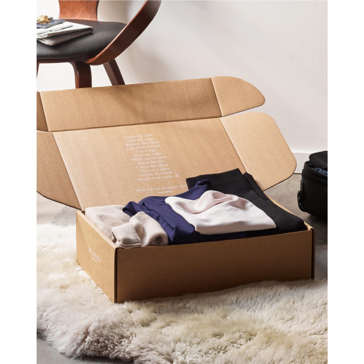 box with clothes folded inside, sitting on the floor with the lid open