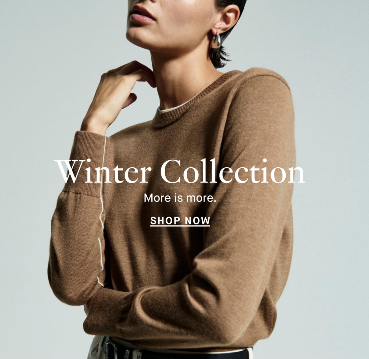 Image of a woman wearing a dark emerald suit in front of a pink background. Baked in text reads: "Winter Collection: More is more. Shop Now"