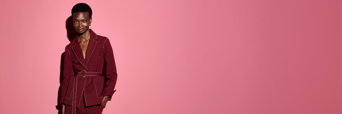 Image of a woman wearing the Grenville jacket in berry jam against a pink background