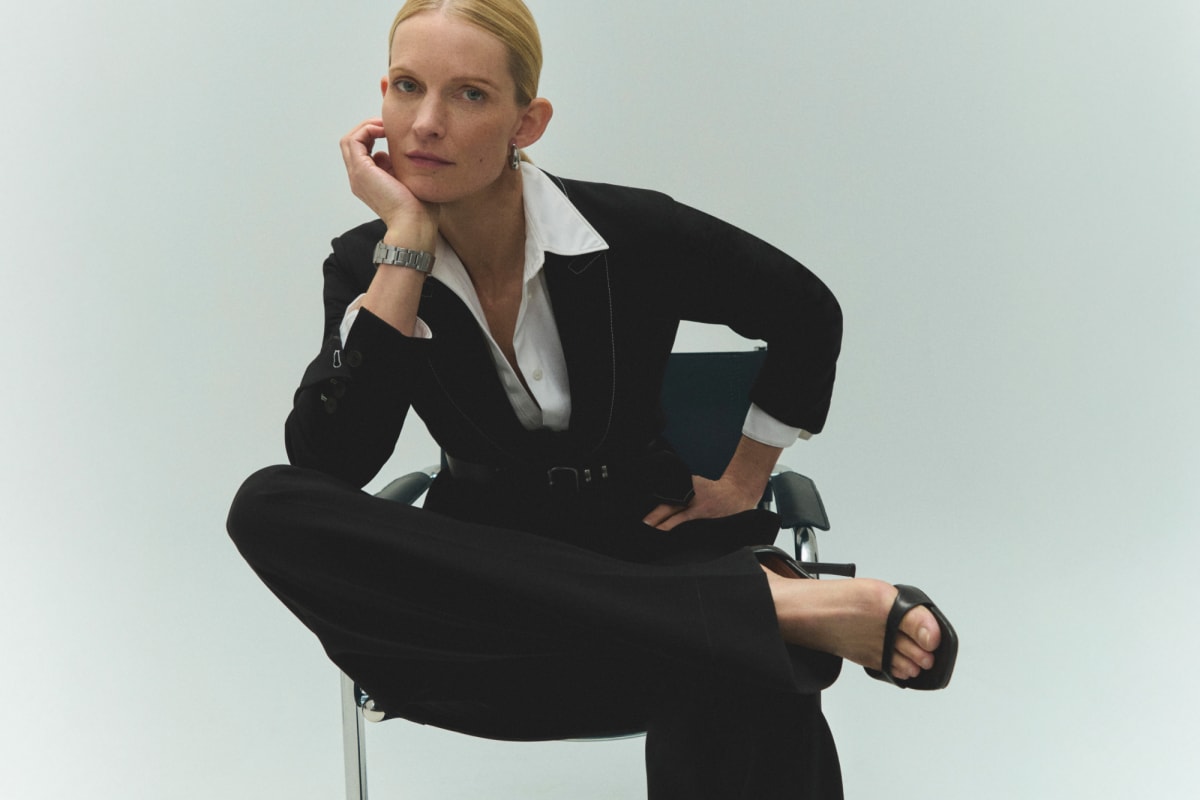 image of a woman sitting on a chair wearing a black suit with a white button down
