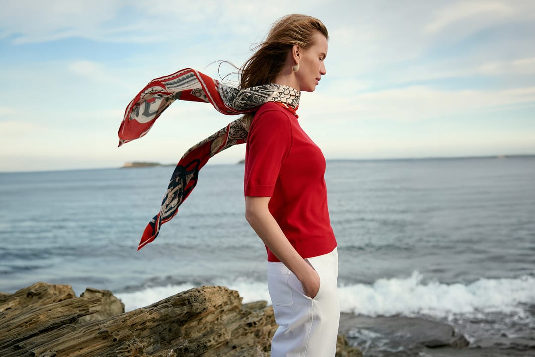 image of a women in the becca tee in red and a scarf on the water