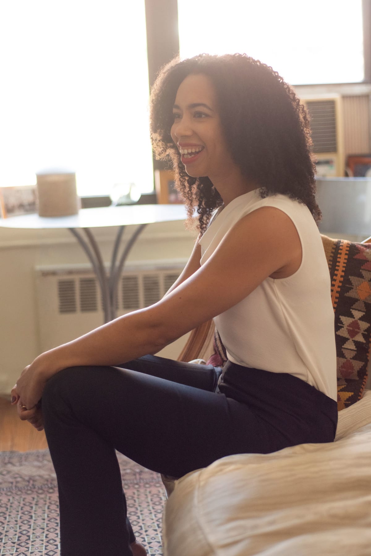 Woman on couch wearing black skinny pants and white sleeveless top