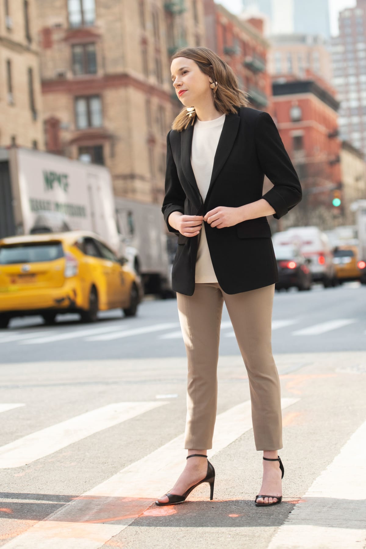 Woman on sidewalk wearing taupe skinny pants and black blazer