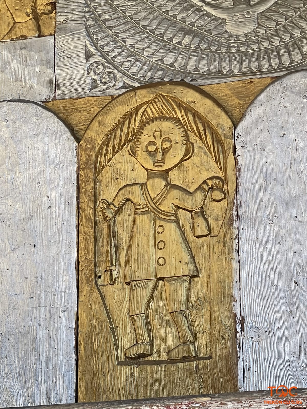 Intricate golden wood carving of a Himalayan deity on an ancient village temple wall