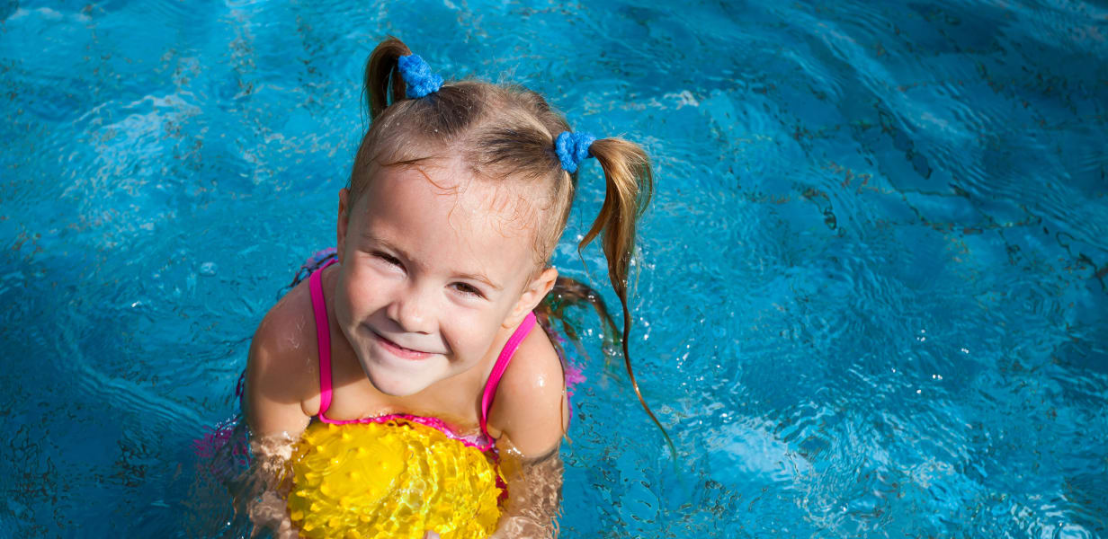 Girl in pool hugging ball for buoyancy