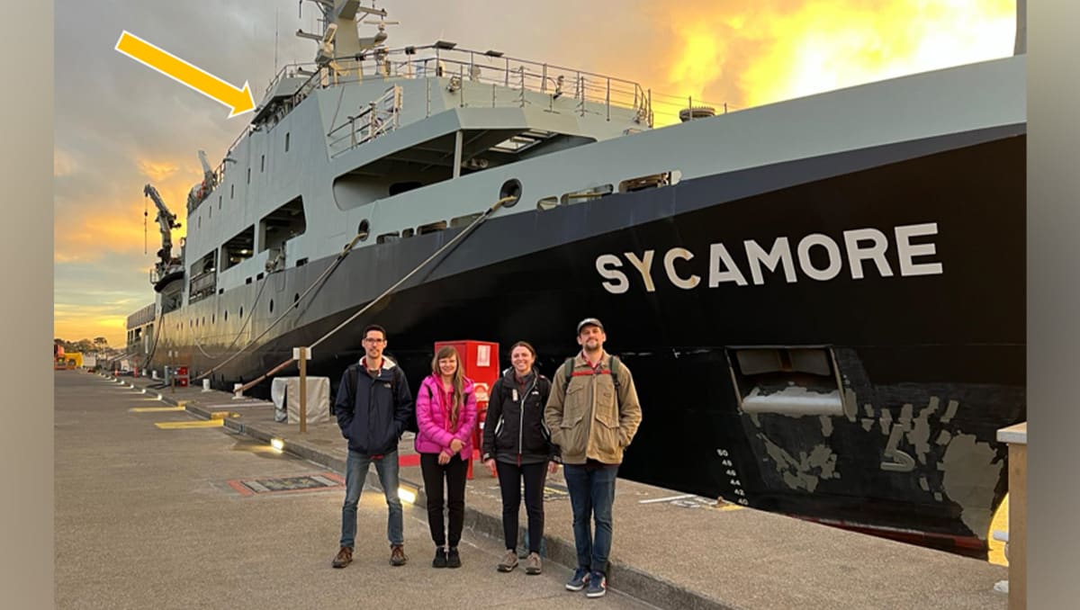 Scientists operating portable atomic clock equipment aboard Australian naval vessel at sea