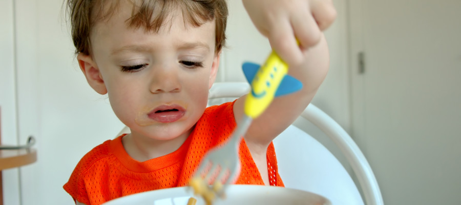 toddler eating with utensils