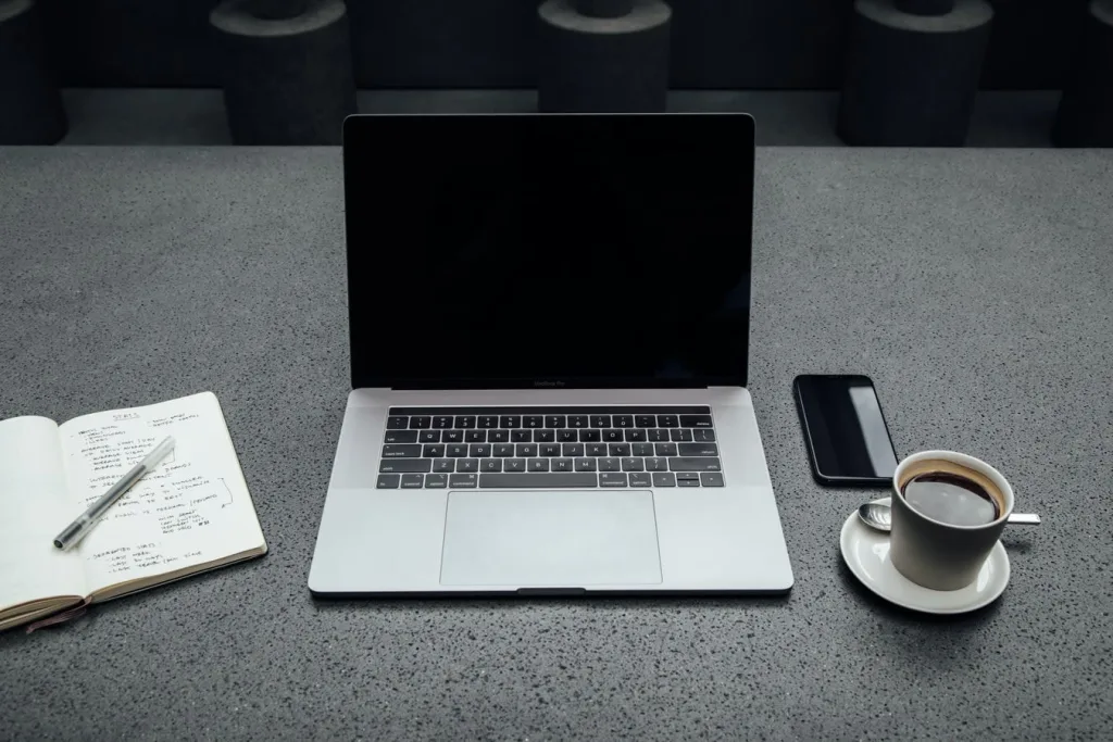 Ordinateur portable avec carnet, smartphone et tasse de café à côté