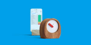 blue background with a phone showing a monday.com board, and a wooden clock