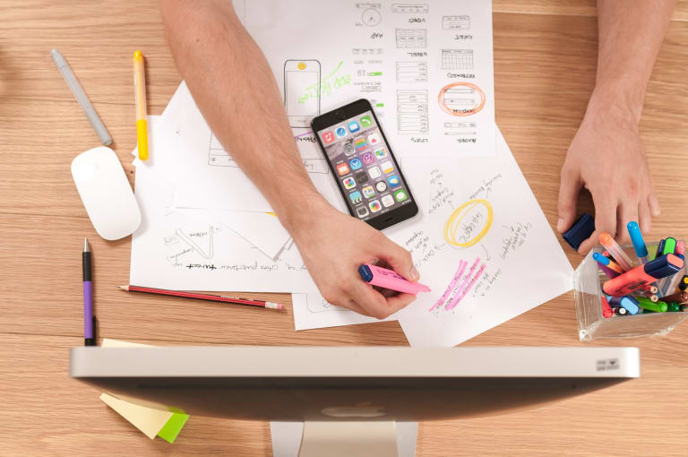 a person planning out a project with highlighters, schedules, and their phone.
