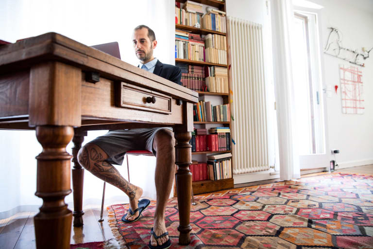 homme assis à un bureau en tenue professionnelle en haut et en short et tong