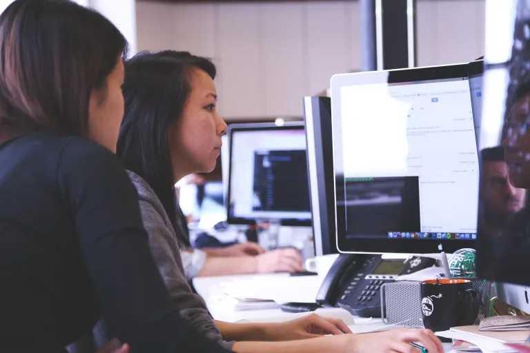 two people sitting at a computer, working on a business project