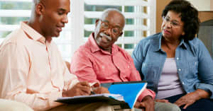 A woman cheerfully discusses family finances with her son, while her husband looks on